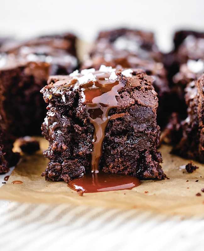 Chocolate brownie with caramel drizzle on a piece of parchment paper
