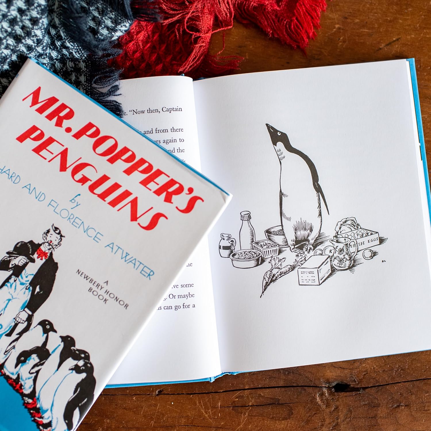 Open book of 'Mr. Popper's Penguins' with illustrations on a wooden surface