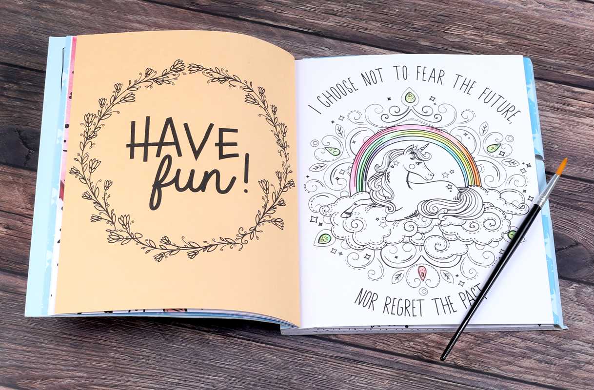 Open coloring book with motivational text and a unicorn illustration on a wooden surface.